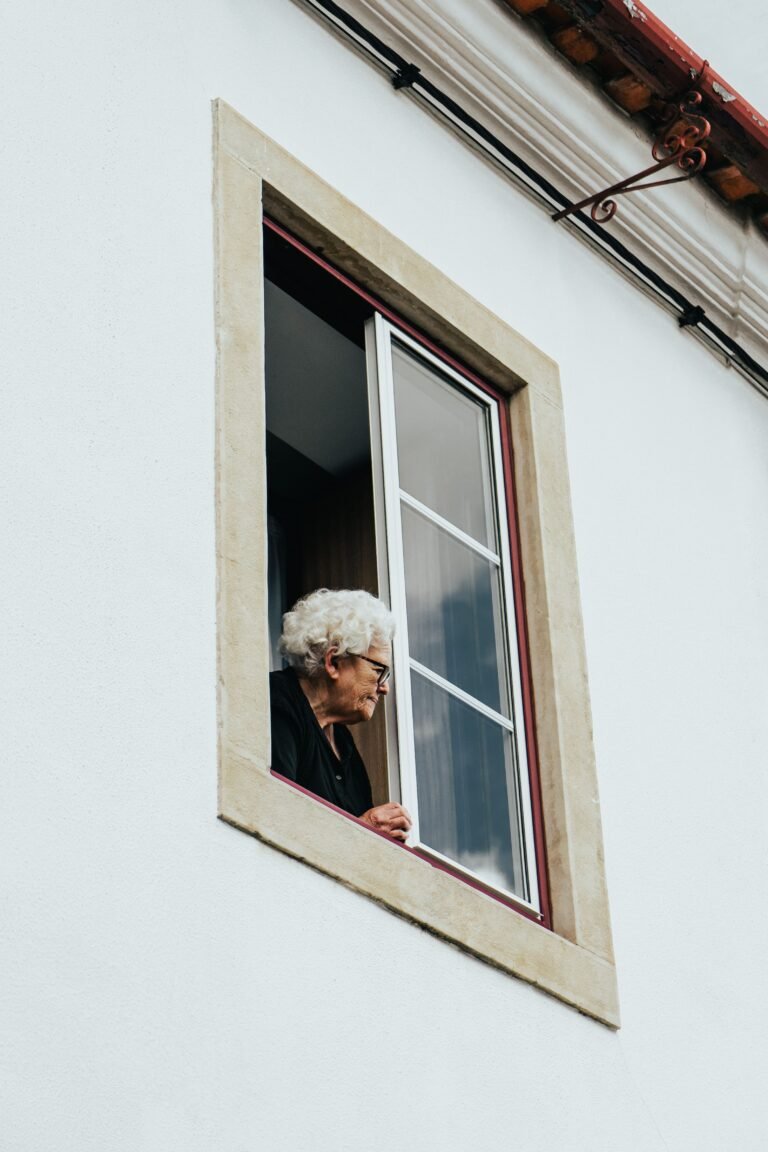 Older woman looking out of her window alone