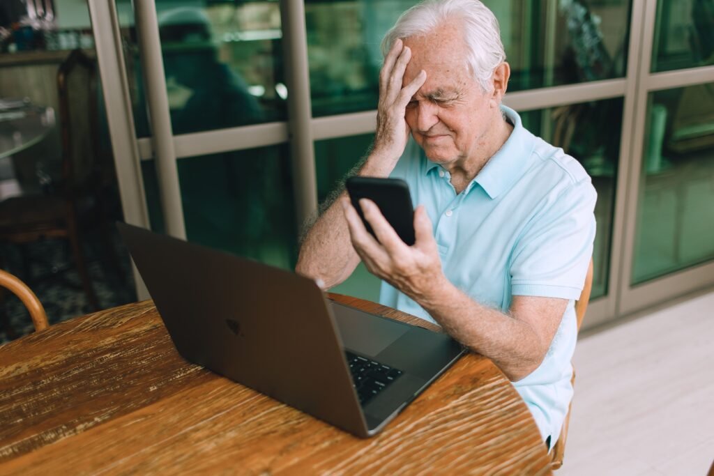 Worried older man on the phone in front of a laptop