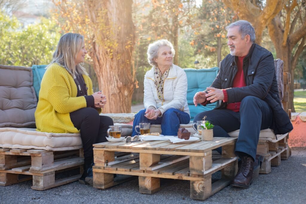 Adult siblings and their aging parents talking together outdoors