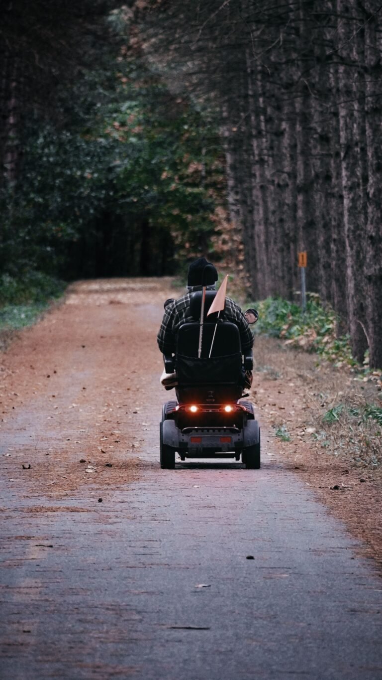 Person riding a mobility scooter along a forest path