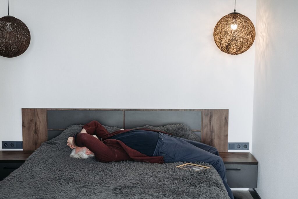 Person lying awake on a bed in a dim bedroom