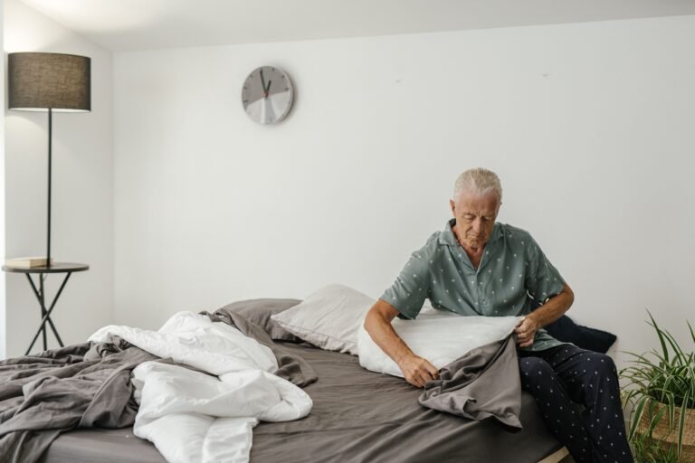 Older man sitting on his bed at home