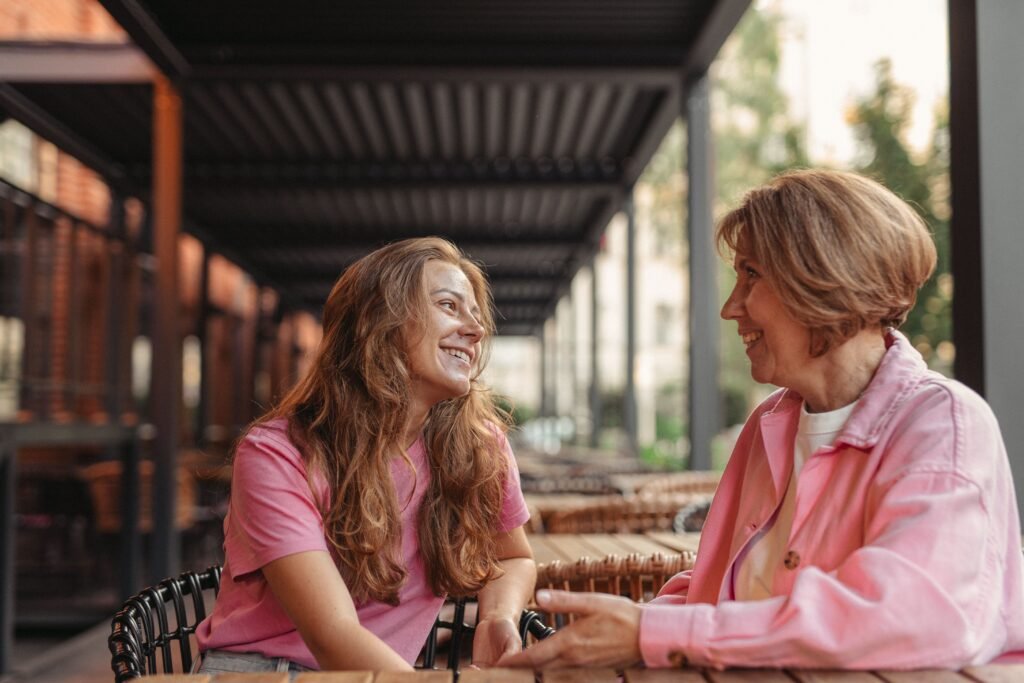 Young woman and her older mother laughing together on a porch