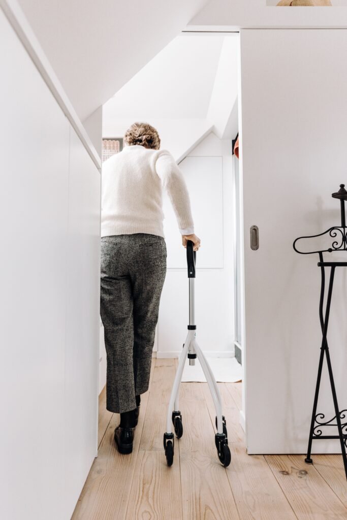Older man walking with a walker in a hallway at home