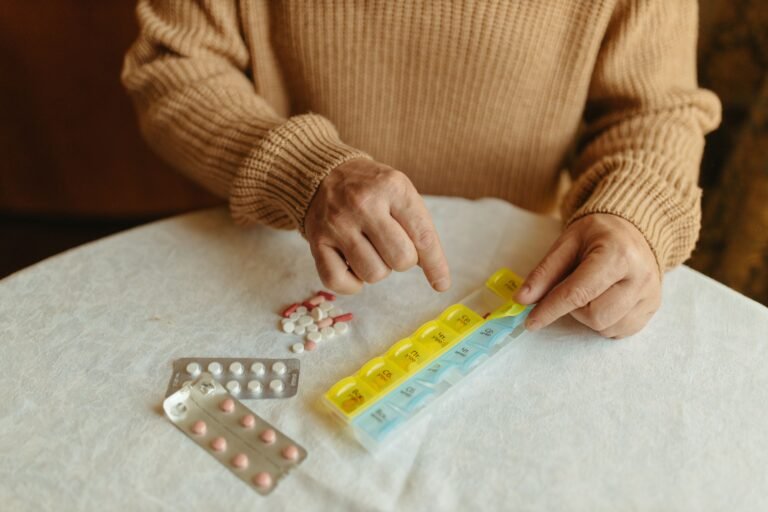 Hands sorting pills into a weekly pill organizer